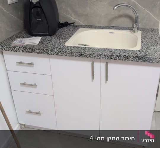 כיור מטבח עם ברז, ארונות ומגב על הרצפה